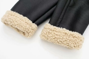 Detail shot of black leather jacket cuff with thick cream faux shearling lining