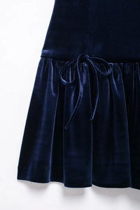 Détail de robe courte en velours marine montrant la taille plissée et le nœud