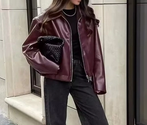 Detail of burgundy leather jacket with silver zipper and lapels in a street style setting