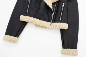 Detailed close-up of a faux leather biker jacket with contrasting white shearling trim