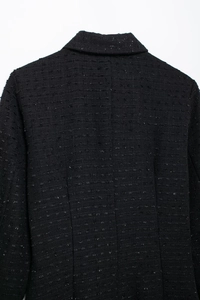 Détails de la robe mini en tweed noir montrant la texture du tissu et le col revers