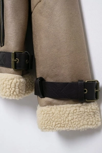 Détail du poignet d'une veste en daim avec doublure en peau de mouton et sangles noires