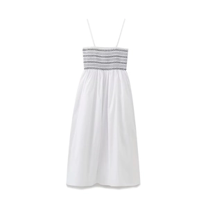 Close-up of white smocked poplin dress featuring black wavy embroidery and thin straps