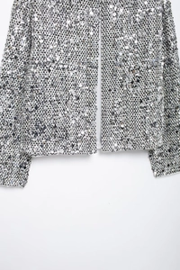 Dettaglio ravvicinato di paillettes d'argento su una giacca di tweed bianca lucida