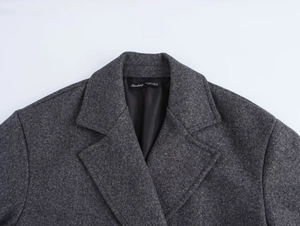 Detail view of double-breasted grey coat collar with textured wool blend and brand label