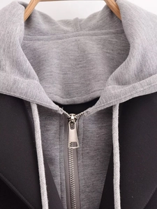 Detail of color-block hooded coat featuring a metallic zipper and woven drawstrings