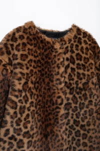 Macro detail of faux fur texture and black lining on leopard print round neck jacket