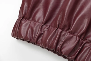 Detailed macro shot of burgundy leather jacket elastic cuff with lychee texture finish