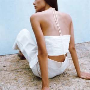 Detailed back view of white halter crop top featuring crinkled fabric and tie-neck design