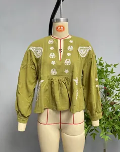 Vue détaillée de la broderie blanche sur le chemisier en coton et lin vert moutarde à col V