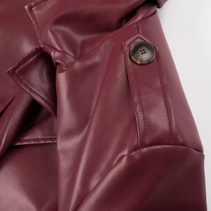 Détail du trench en cuir bordeaux montrant l'épaulette, le revers et le bouton ambré