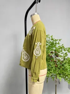 Détail du chemisier vert avec broderie paisley blanche et poignets plissés sur la manche