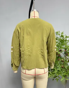 Détail du haut vert olive avec des broderies florales blanches sur les manches