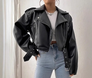Dettaglio di una giacca biker corta in ecopelle nera con zip metalliche e cintura in vita
