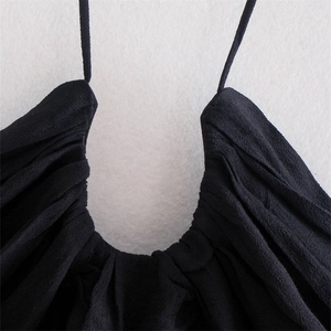 Detail of black U-neck halter top featuring pleated fabric texture and ruched neckline