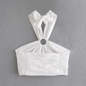 Detail of white halter crop top featuring a metal ring buckle and bow shoulder straps
