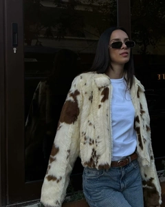 Détail d'une veste courte en fausse fourrure à motif vache marron et blanc avec zip