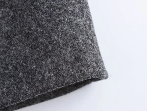 Close-up of thick dark grey wool fabric texture and stitching detail on the coat sleeve