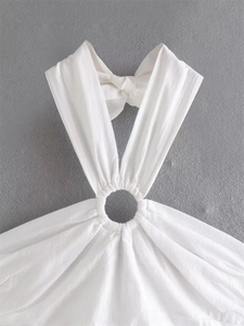 Detail of white halter neck top featuring metallic ring buckle and ruched fabric texture
