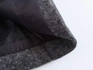 Macro detail of dark grey wool coat showing neat stitching and smooth black silk lining