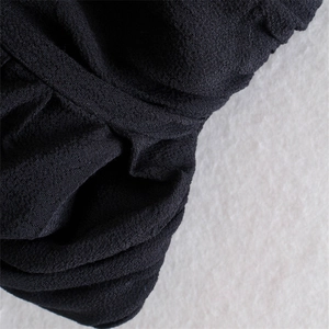 Close-up of black textured crepe fabric detail and fine stitching on a U-neck halter top