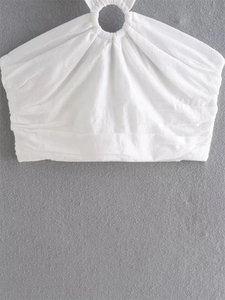 Detail of white halter neck top featuring a textured fabric and central ring buckle