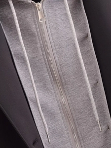 Detail of metal zipper and drawstring on a grey knit hooded coat for women
