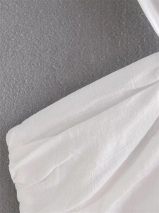 Detail of white knotted summer top showing premium fabric texture and pleated ring buckle