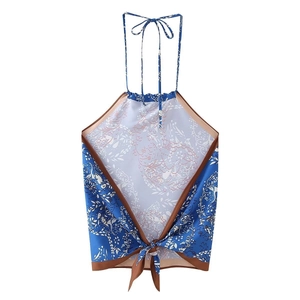 Dettaglio del top blu allacciato al collo con bordo marrone e motivi floreali