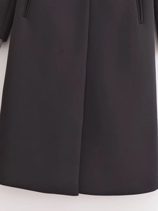 Detail of premium black long coat showing straight hem and invisible pocket craft