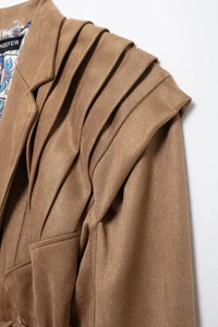 Detail of layered pleated shoulder design on brown faux suede jacket with soft texture