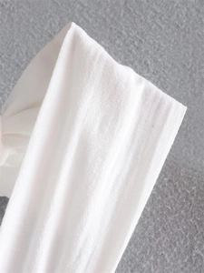 Detailed close-up of white breathable fabric with vertical texture and soft knot detail