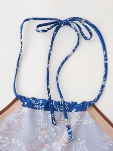 Dettaglio del top allacciato al collo floreale con motivi blu, bordi marroni e fiocco