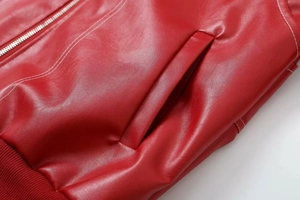 Détail de la veste en cuir PU rouge avec coutures contrastées et zip métallique