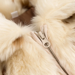 Détail d'un manteau en fausse fourrure beige avec fermeture éclair et doublure marron