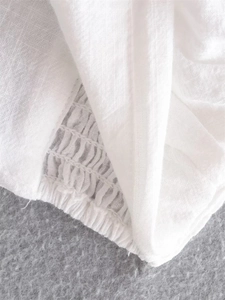 Detail of white blouse showing elastic smocking and pleated fabric texture for women