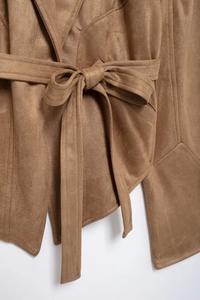 Detailed close-up of brown suede jacket featuring waist belt bow and fine stitching