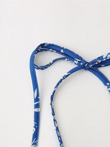 Dettaglio del laccio al collo su top blu scuro con stampa floreale e trama liscia del tessuto