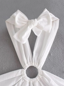 Detailed close-up of white halter top featuring a large bow and central metal ring buckle