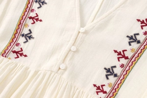 Detail of V-neck embroidery pattern and textured cotton linen fabric on a beige dress