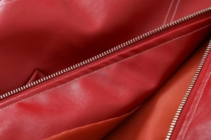 Détail d'une veste en cuir rouge avec texture litchi et fermeture éclair en métal argenté