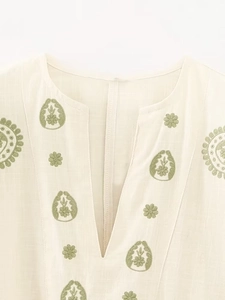Détail de la broderie florale verte sur le chemisier en coton et lin beige