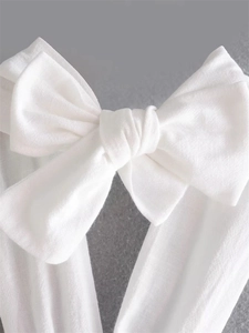 Macro view of white linen bow detail showing natural woven fabric texture and knot