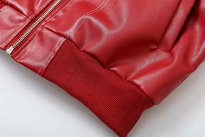 Détail d'une veste en similicuir rouge avec fermeture éclair argentée et coutures blanches