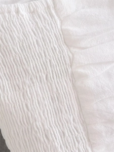 Detailed view of the white smocking fabric and shirred elastic ruffles on the top