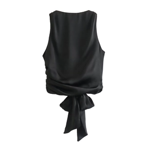 Detail of black satin sleeveless top featuring a pleated hem and bow tie detail