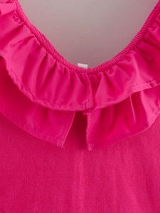 Detailed view of dark pink ribbed knit fabric and ruffle neckline on a summer romper