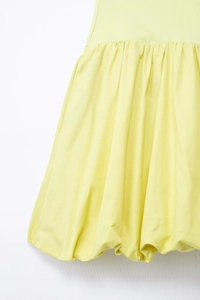 Détail d'une robe courte jaune clair avec un ourlet bulle volumineux et taille plissée