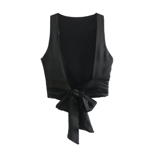 Detail of backless satin crop top with large decorative bow in glossy black fabric