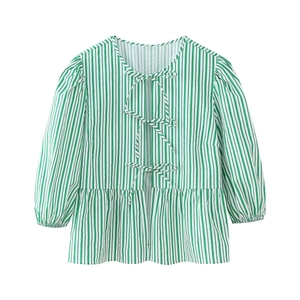 Détail d'une chemise à rayures vertes et blanches avec nœuds et ourlet à volants